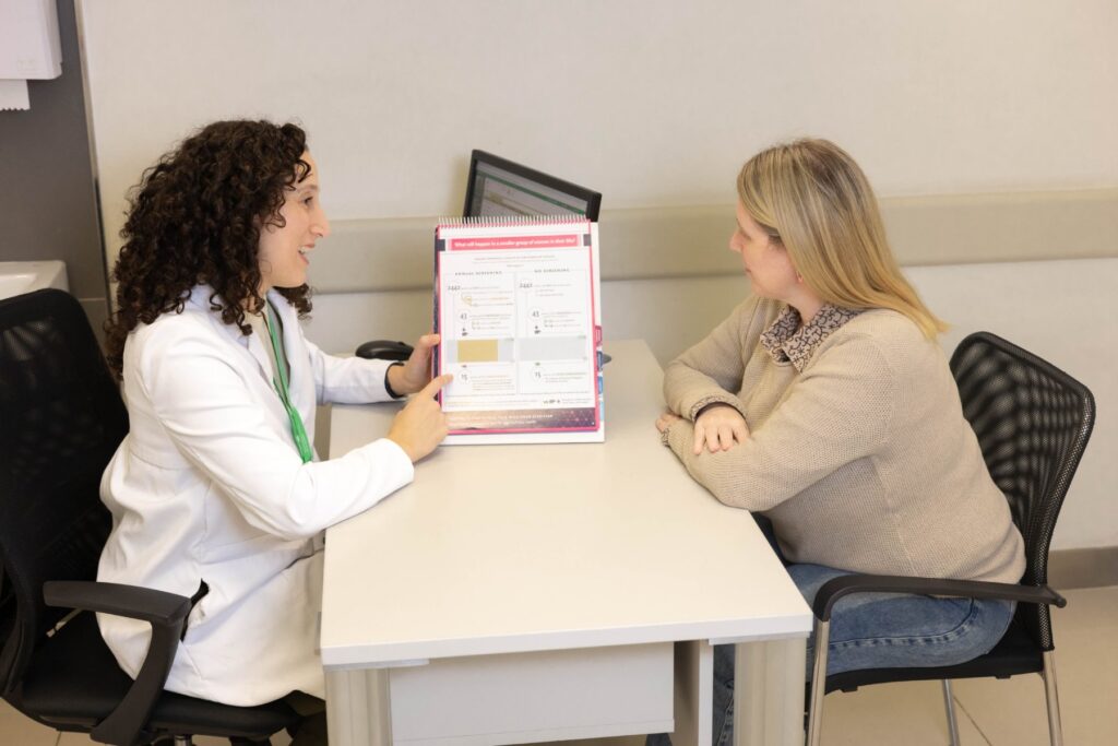 Profesional conversa con una paciente usando un material de apoyo para decisiones compartidas